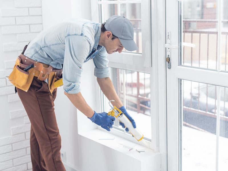 A man repairing window seals in a property.