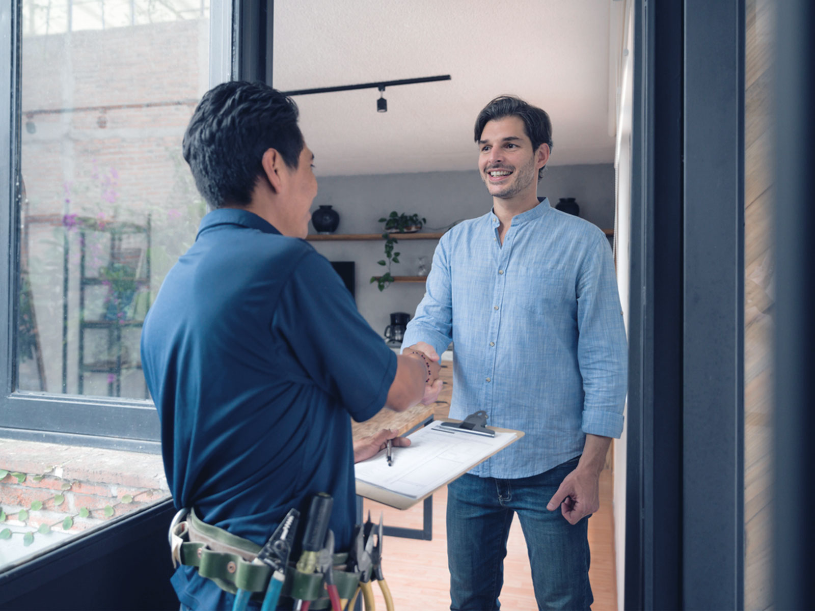 A property owner standing outside his kitchen with a handy man discussing maintenance in the property.