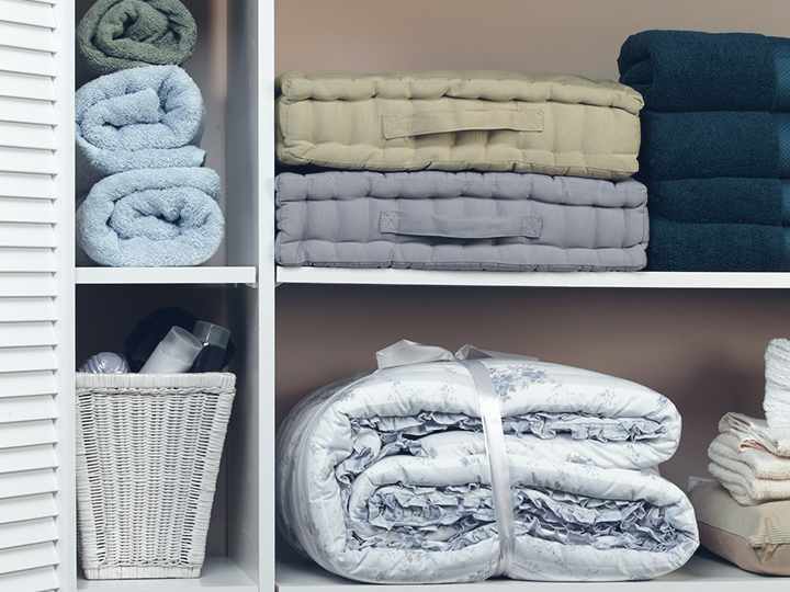 White linen cupboard with towels, cushions and bedding