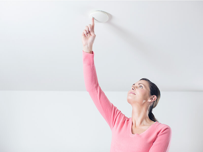 Woman turning on a smoke alarm