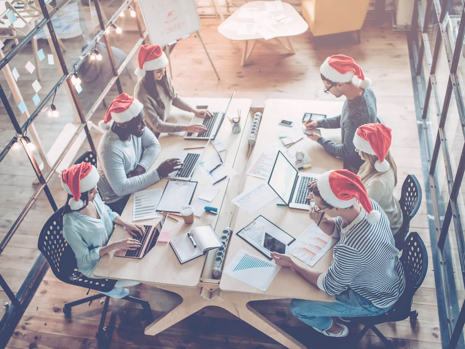 Team sitting at table with Christmas hats on.