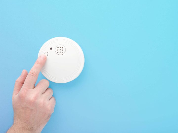 Hand pressing a smoke alarm.