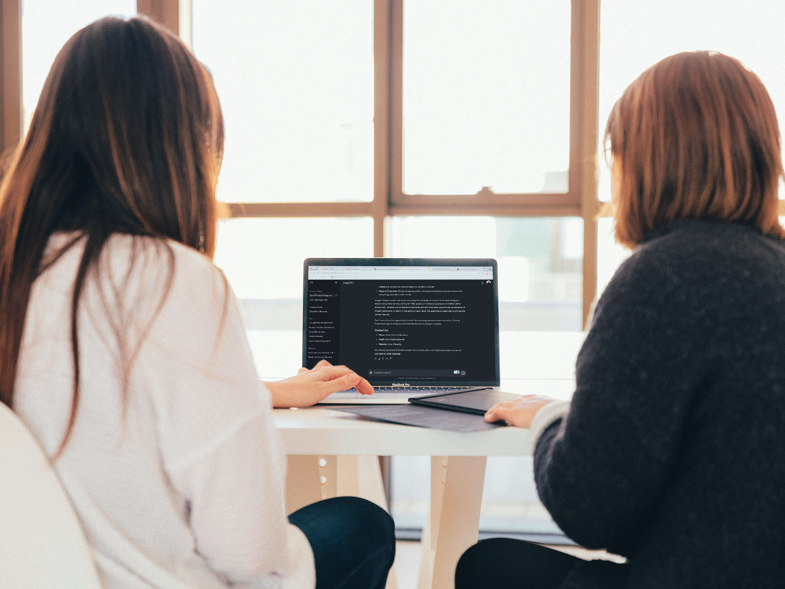 Two workers using ChatGPT on laptop